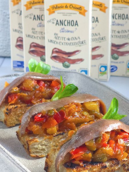 Tostas de pisto de verduras con anchoas en conserva y hojas de canónigo
