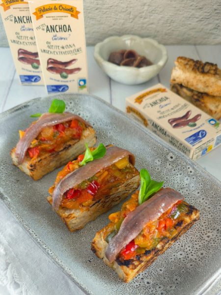 Varias tostas de pisto casero con anchoas dispuestas de forma apetitosa, listas para ser degustadas